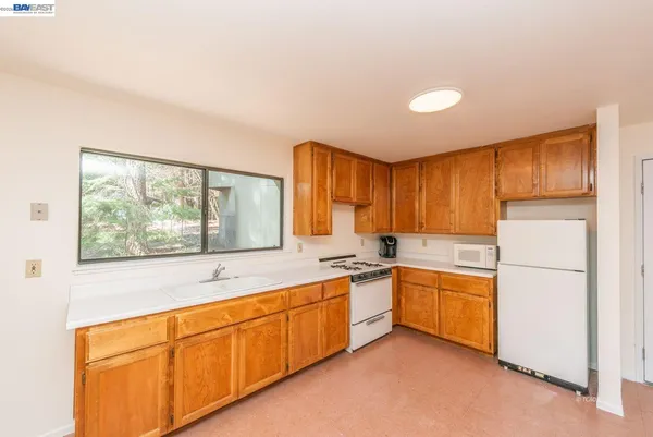 a view of a kitchen with a sink and dishwasher a oven with white cabinets