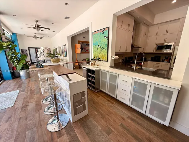 a large white kitchen with stainless steel appliances granite countertop a stove and a wooden floors