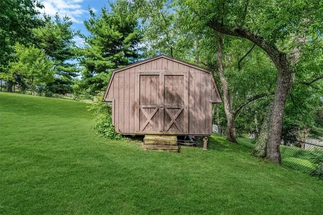 a view of backyard with a barn and large trees
