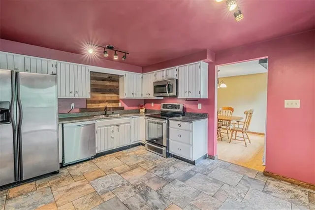 a kitchen with granite countertop a refrigerator stove top oven and sink