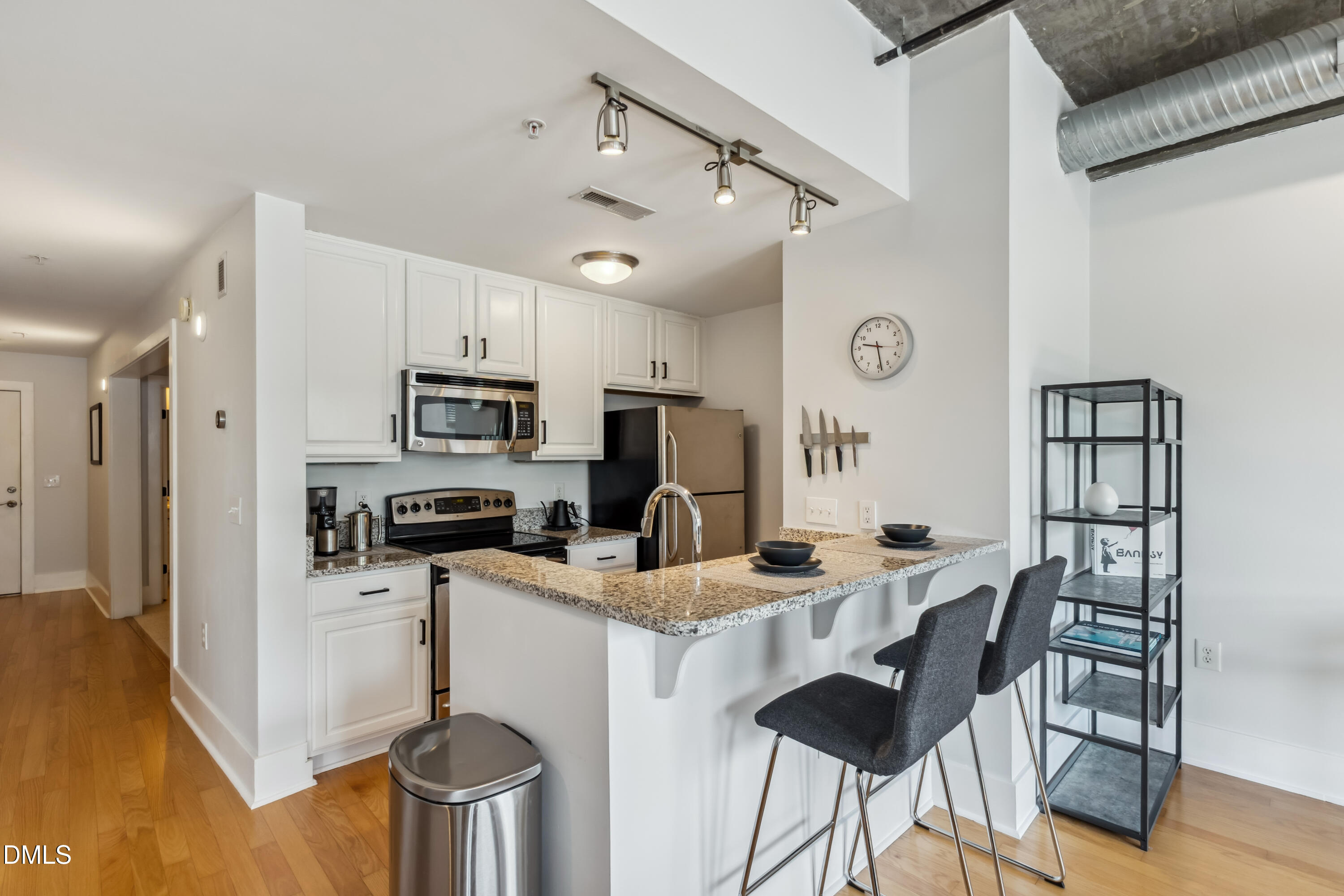 444 South Blount Street, Unit 209 Raleigh, NC 27601 - Photo 5 of 19 a kitchen with stainless steel appliances kitchen island granite countertop a stove a refrigerator a sink a dining table and chairs with wooden floor