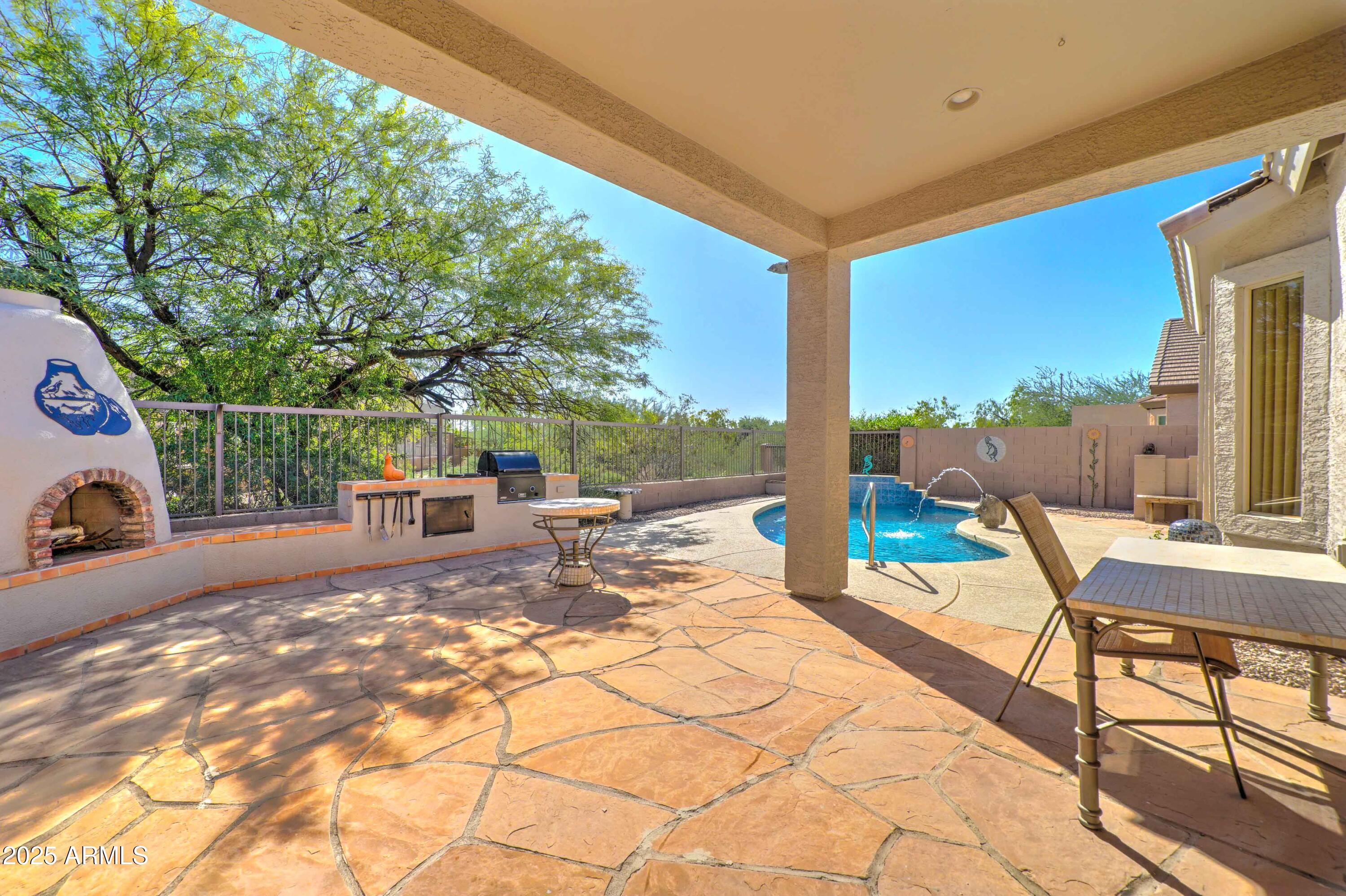 3055 North Red Mountain, Unit 74 Mesa, AZ 85207 - Photo 35 of 38 a view of a patio with a dining table and chairs with wooden fence
