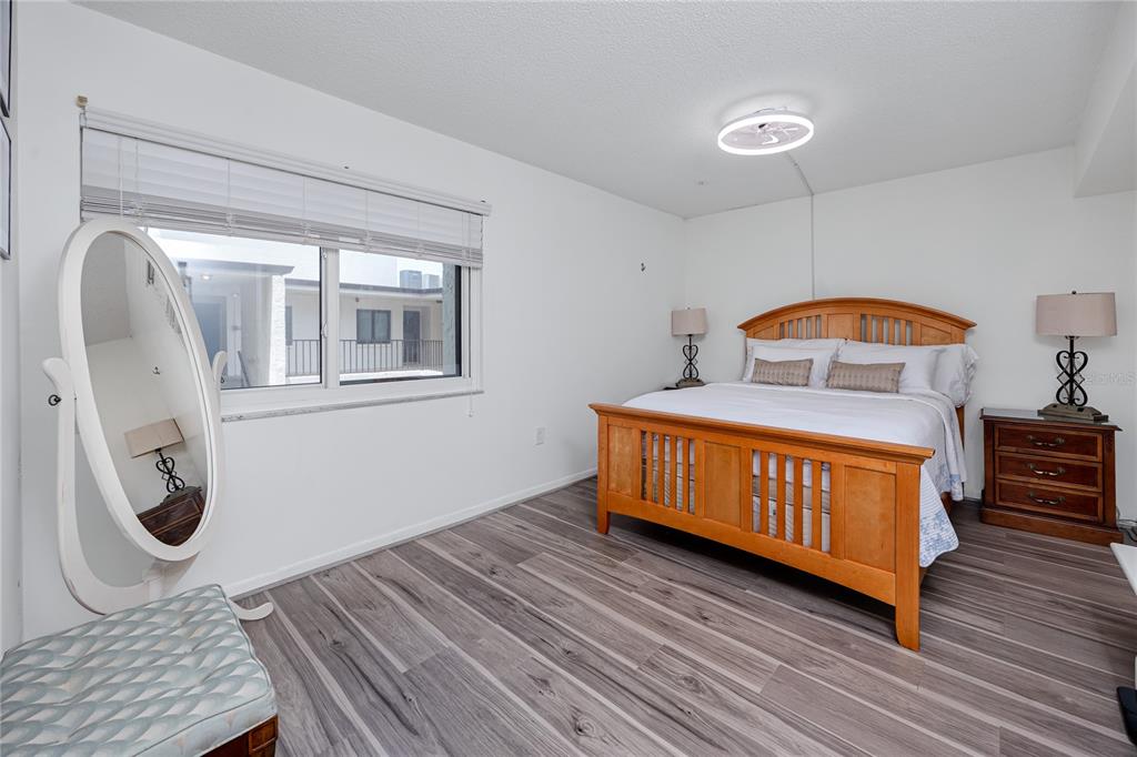 2207 Belleair Road, Unit B30 Clearwater, FL 33764 - Photo 13 of 39 a bedroom with a bed a mirror on desk and wooden floor