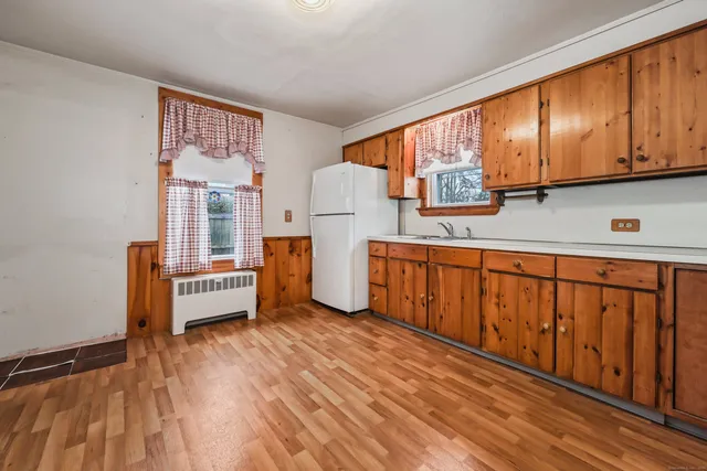 a kitchen with stainless steel appliances granite countertop a refrigerator a stove and a sink with wooden floors