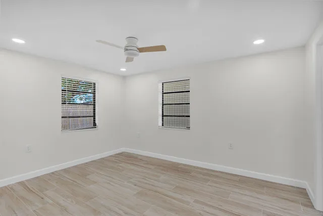 an empty room with wooden floor closet and windows