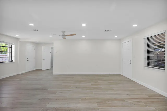 an empty room with wooden floor and windows