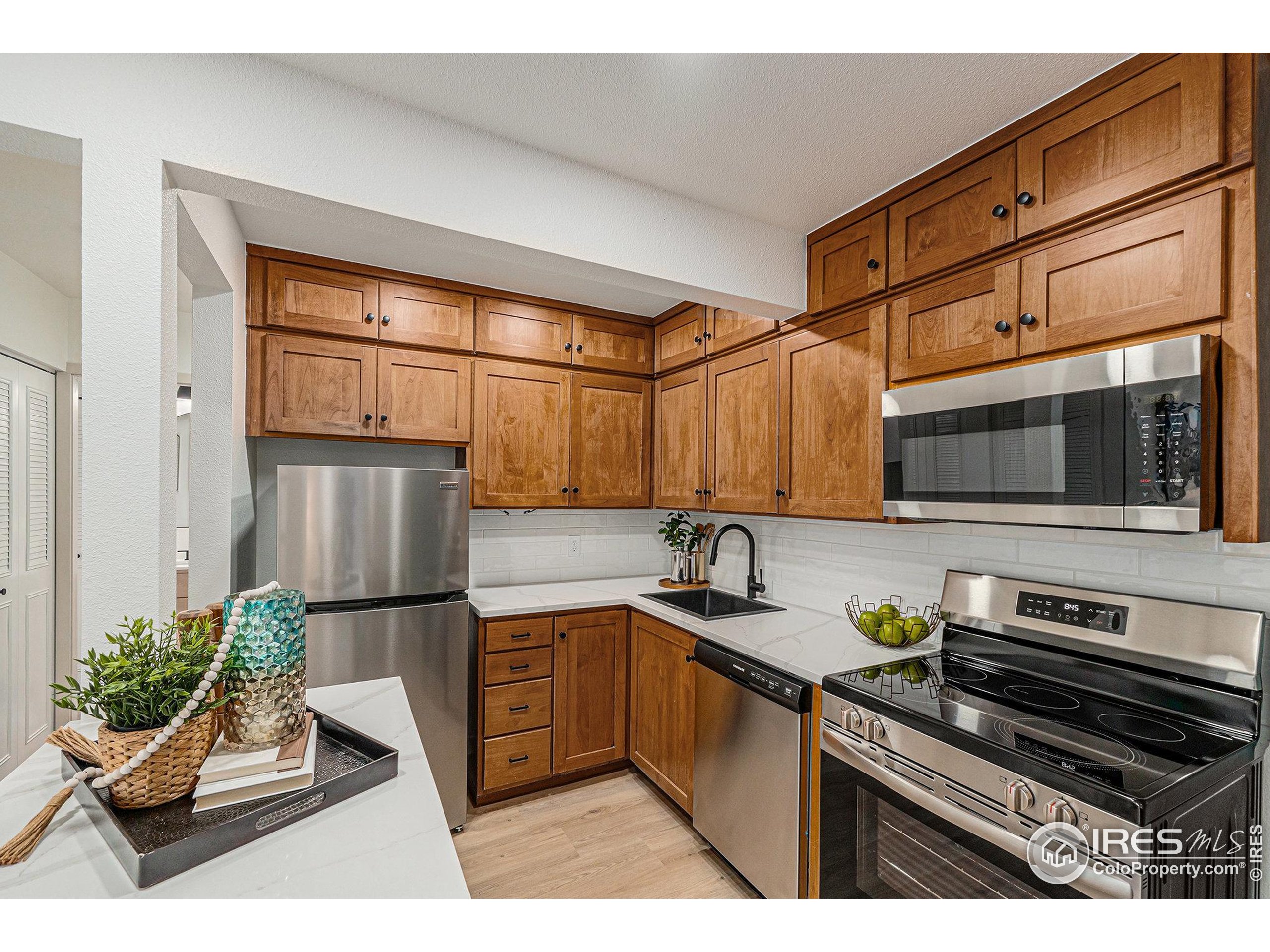 620 Mathews Street, Unit 104 Fort Collins, CO 80524 - Photo 8 of 32 a kitchen with stainless steel appliances kitchen island granite countertop a sink and a refrigerator