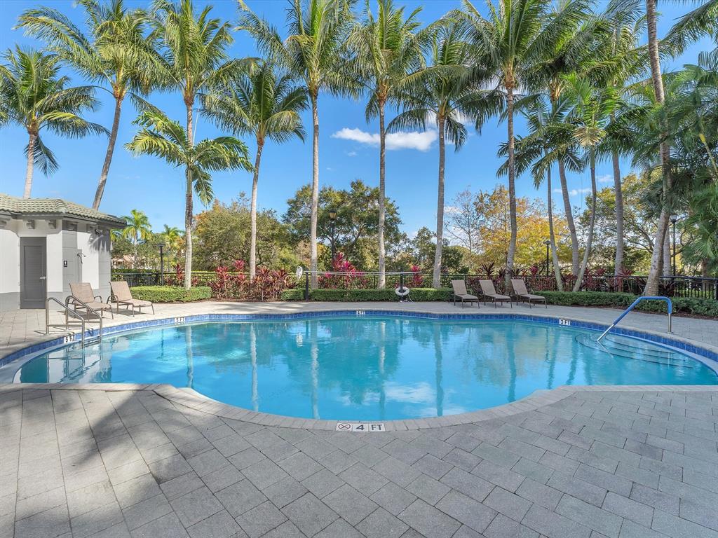 1660 Renaissance Commons Boulevard, Unit 2628 Boynton Beach, FL 33426 - Photo 34 of 49 a view of a swimming pool with a lawn chair and palm trees
