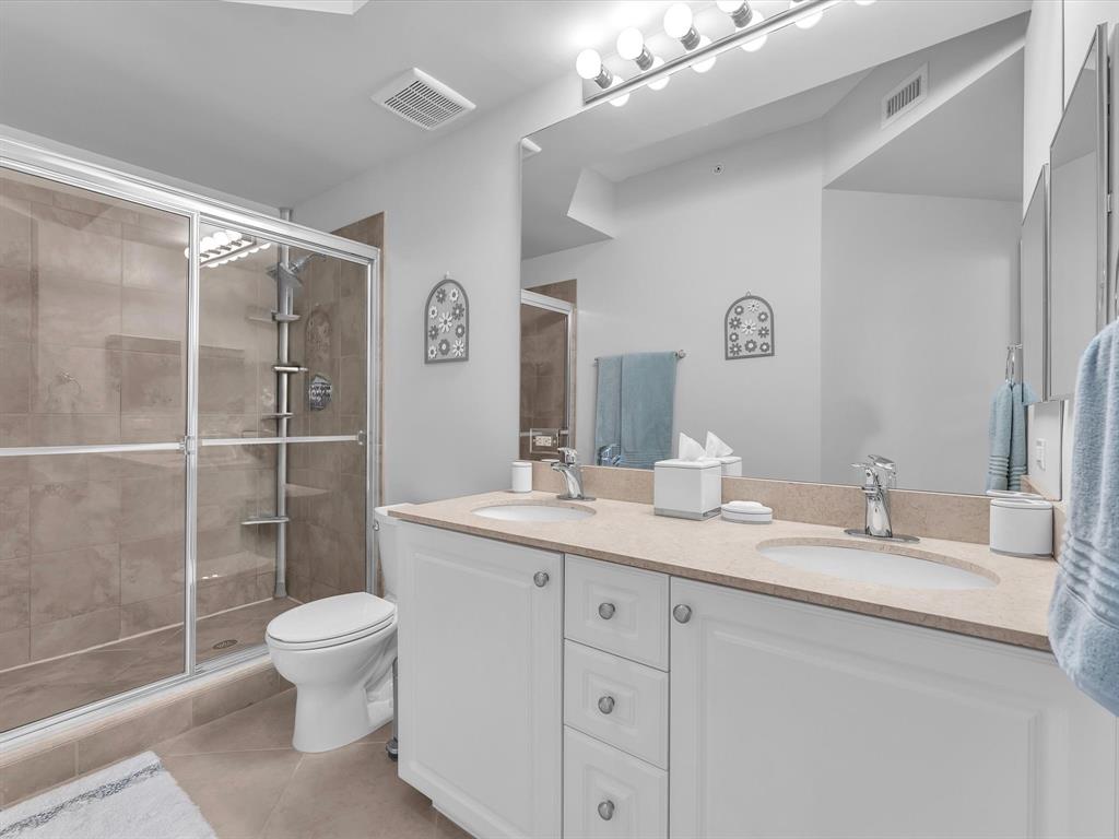 1660 Renaissance Commons Boulevard, Unit 2628 Boynton Beach, FL 33426 - Photo 5 of 49 a bathroom with a granite countertop sink a toilet a mirror and shower