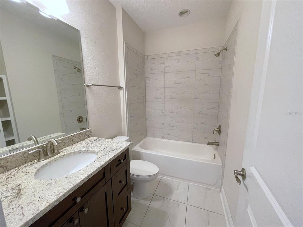 2411 West North A Street, Unit 2 Tampa, FL 33609 - Photo 12 of 19 a bathroom with a granite countertop sink a toilet and bathtub