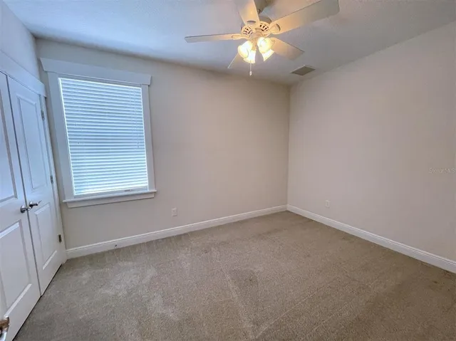 an empty room with a window and a fan