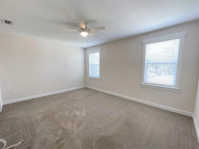 an empty room with windows and fan