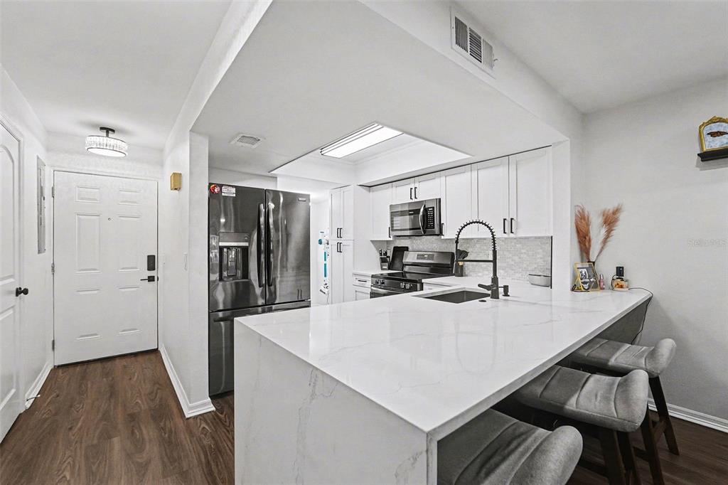 5197 Silent Loop, Unit 121 New Port Richey, FL 34652 - Photo 8 of 36 a kitchen with stainless steel appliances a sink a stove a refrigerator cabinets and a dining table