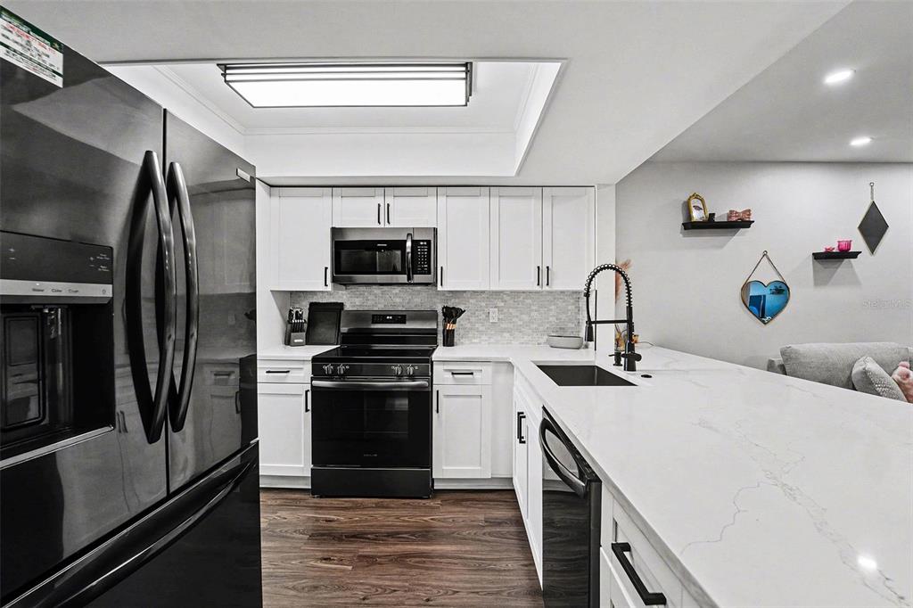 5197 Silent Loop, Unit 121 New Port Richey, FL 34652 - Photo 9 of 36 a kitchen with stainless steel appliances a sink stove refrigerator and cabinets