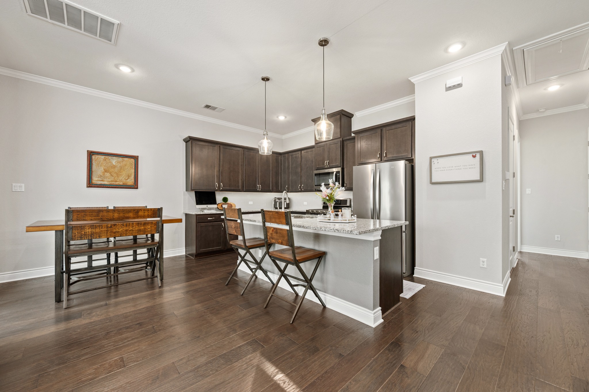 372 Adams Street Georgetown, TX 78628 - Photo 8 of 33 a open kitchen view with stainless steel appliances granite countertop a stove a refrigerator a oven a dining table and chairs with wooden floor