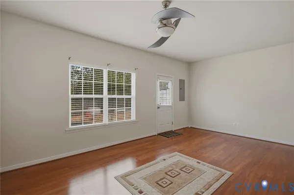 an empty room with wooden floor and ceiling fan