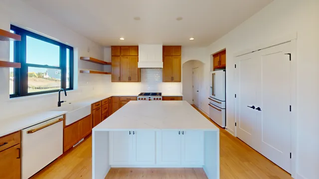 a kitchen with stainless steel appliances a refrigerator a sink dishwasher with wooden floor and cabinets