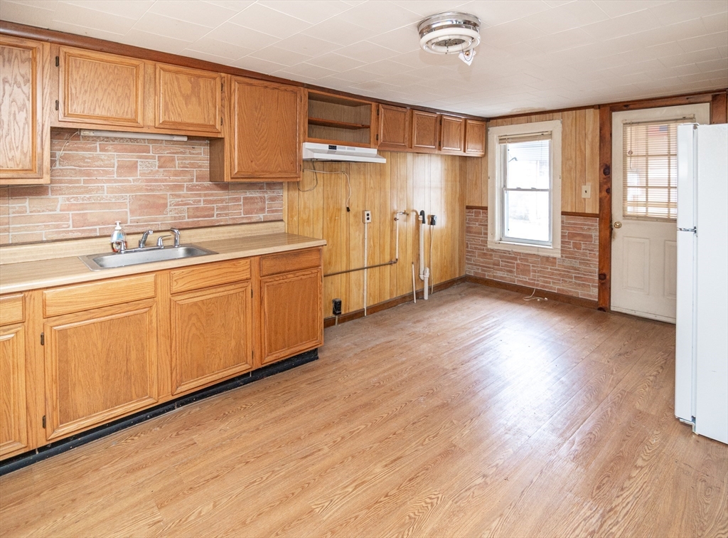 21 Park Street Webster, MA 01570 - Photo 4 of 38 a kitchen with stainless steel appliances granite countertop a refrigerator a sink dishwasher and wooden cabinets with wooden floor