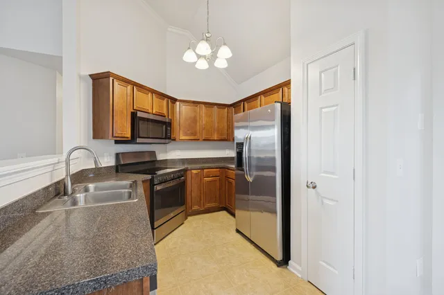 a kitchen with stainless steel appliances granite countertop a refrigerator a stove a sink and a microwave