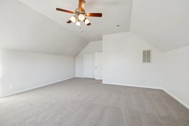 a view of an empty room with a chandelier fan