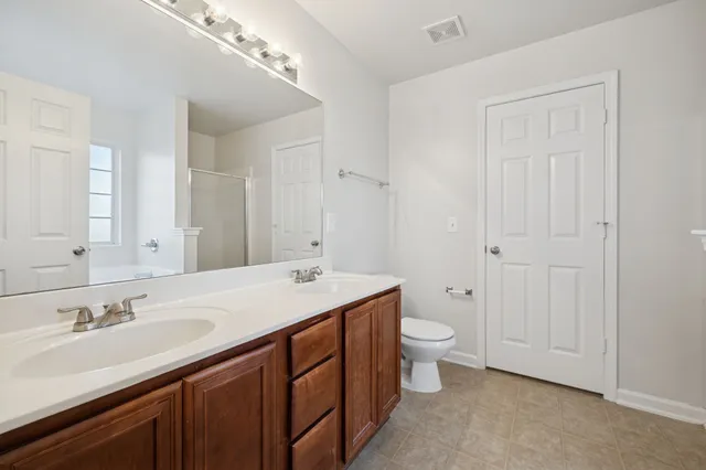 a bathroom with a granite countertop sink a toilet and a large mirror