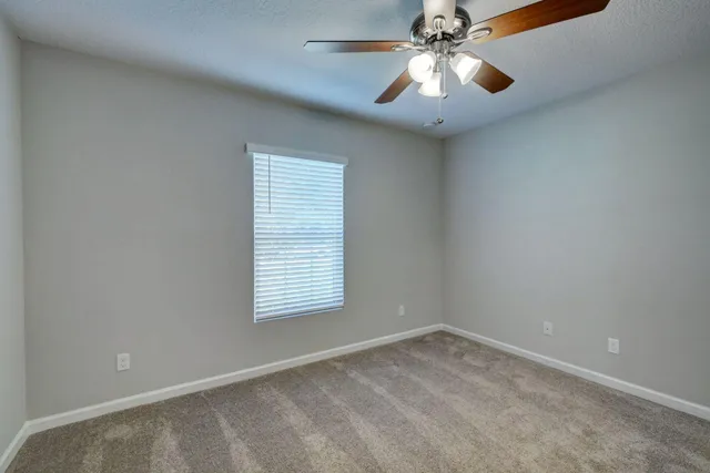 an empty room with a window and a fan