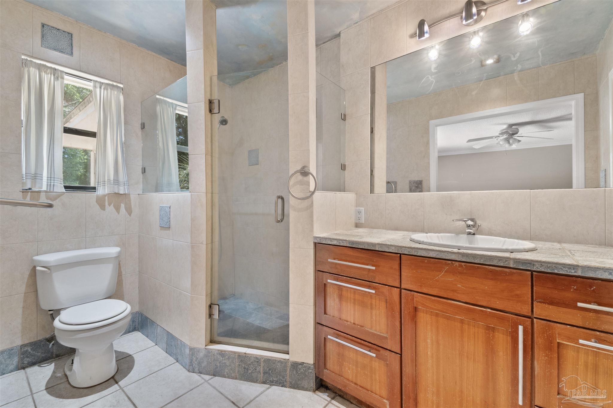 1151 Stone Bridge Road Pensacola, FL 32514 - Photo 24 of 52 a bathroom with a toilet a sink and glass door