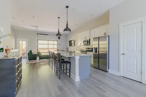 a kitchen with stainless steel appliances granite countertop a refrigerator a stove a sink dishwasher a dining table and chairs with wooden floor