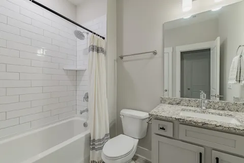 a bathroom with a granite countertop sink a toilet and shower