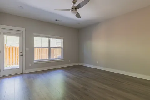 an empty room with wooden floor and windows