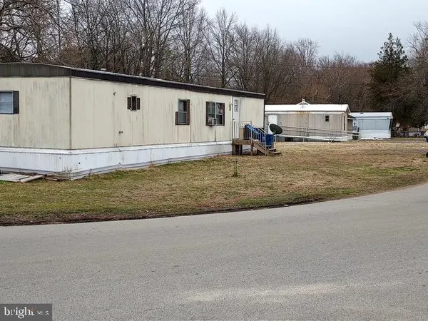 a view of a house with backyard and trees in the background
