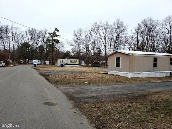 a view of a white house with a big yard and large trees