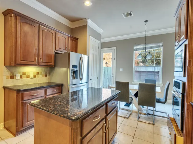a kitchen with granite countertop a counter space dining table and stainless steel appliances