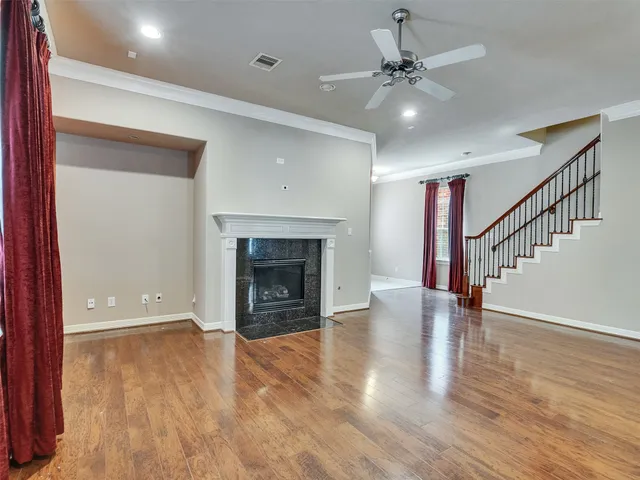 a view of an empty room with wooden floor a fireplace and a window