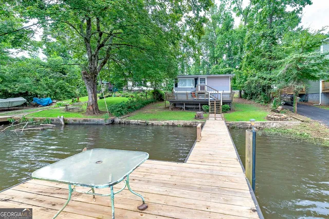 a view of a wooden deck and lake with trees in the background