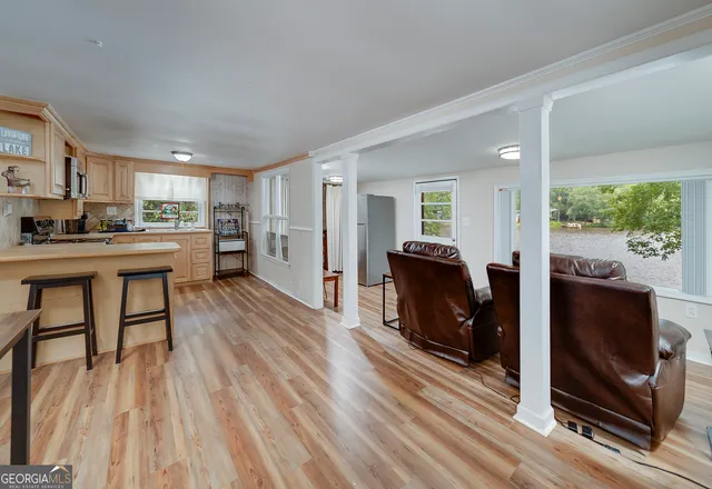 a living room with stainless steel appliances furniture a fireplace and a flat screen tv