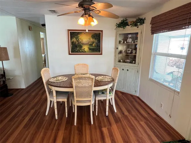 a dining room with wooden floor a chandelier a wooden table and chairs