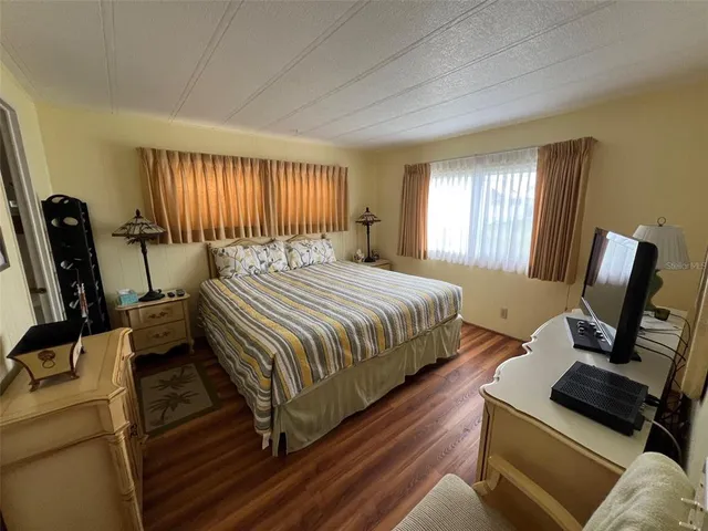 a bedroom with a bed wooden floor and a television