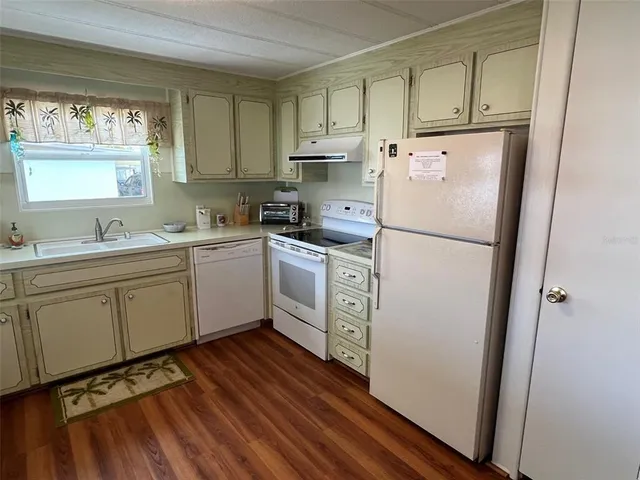 a kitchen with sink a refrigerator and white cabinets