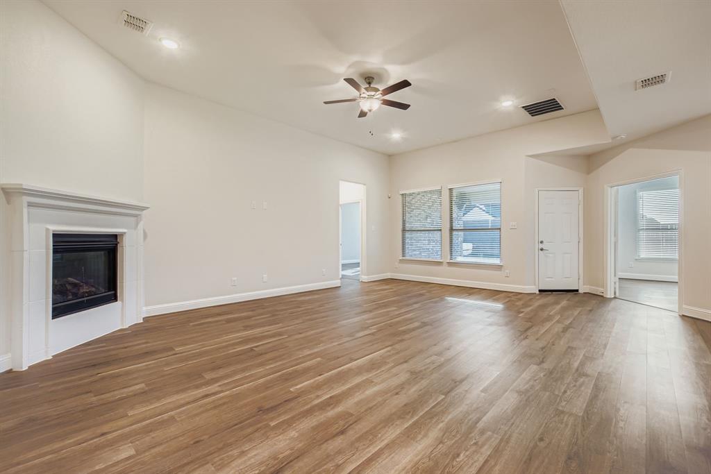312 Magnolia Drive Oak Point, TX 75068 - Photo 4 of 28 Unfurnished living room with wood finished floors, a glass covered fireplace, a ceiling fan, and recessed lighting