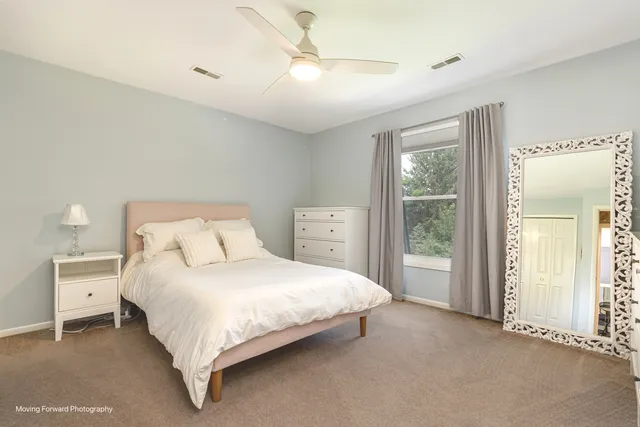 a bedroom with a large bed and a chandelier fan