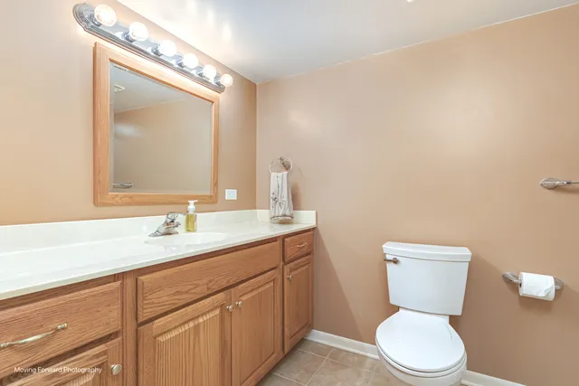 a bathroom with a granite countertop toilet sink and mirror