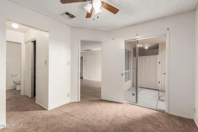 an empty room with closet and a chandelier fan