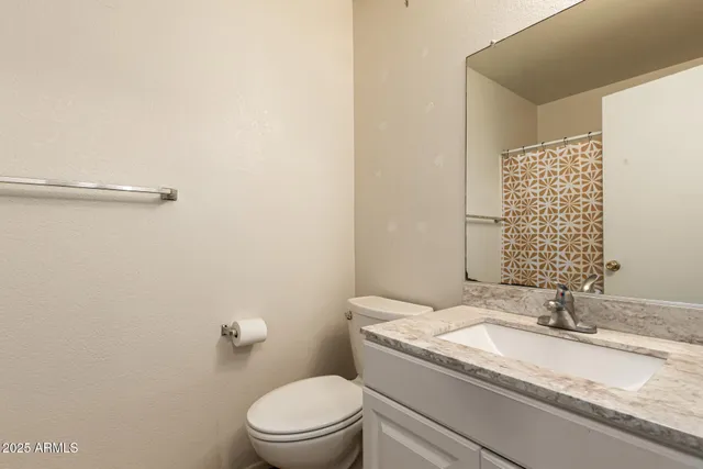 a bathroom with a granite countertop sink a toilet and a mirror