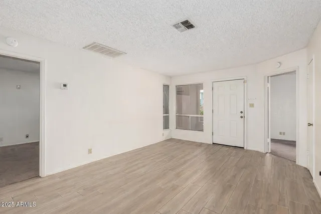 a view of an empty room with wooden floor and closet