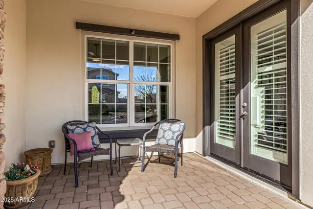 a balcony with table and chairs and potted plants