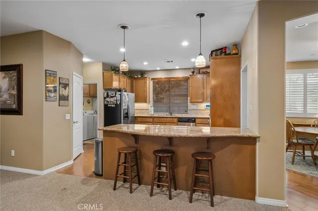 a kitchen with kitchen island a dining table chairs stainless steel appliances and cabinets