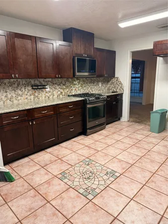 a kitchen with stainless steel appliances kitchen island granite countertop a sink stove and refrigerator