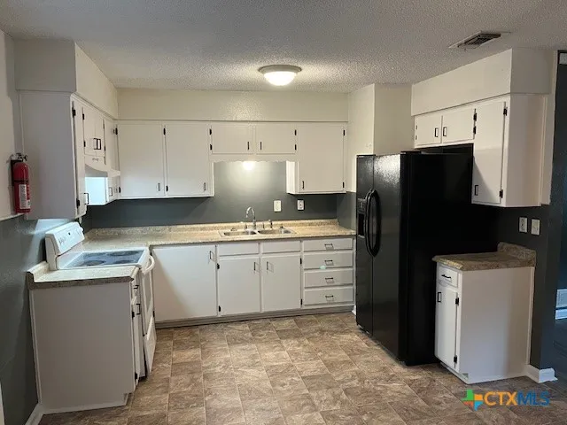 a kitchen with a refrigerator stove and white cabinets