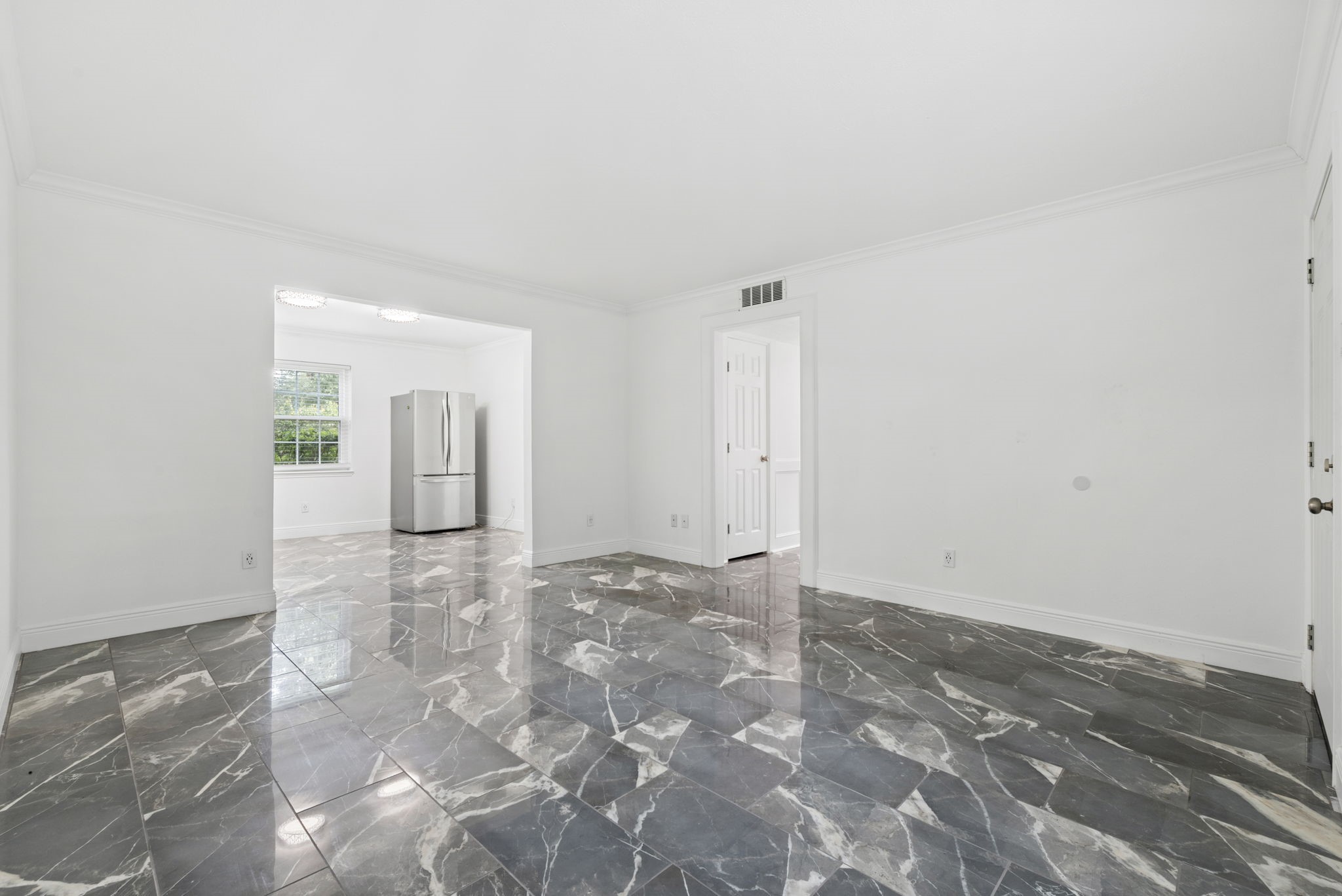 7900 Westheimer Road, Unit 121 Houston, TX 77063 - Photo 10 of 23 Spacious living area with elegant marble flooring, abundant natural light, and a seamless flow into the modern kitchen featuring stainless steel appliances.
